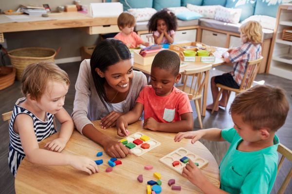 Teacher and pupils using wooden shapes in montessori school