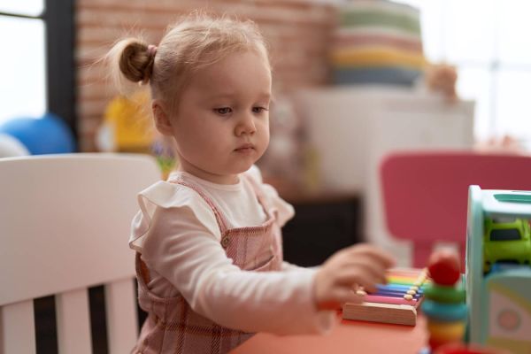 Adorable caucasian girl playing with toys sitting table kindergarten